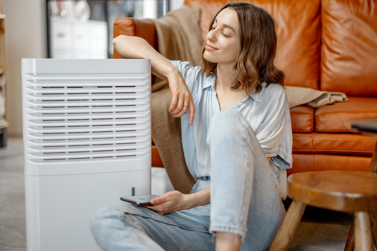A woman sitting next to an air purifier